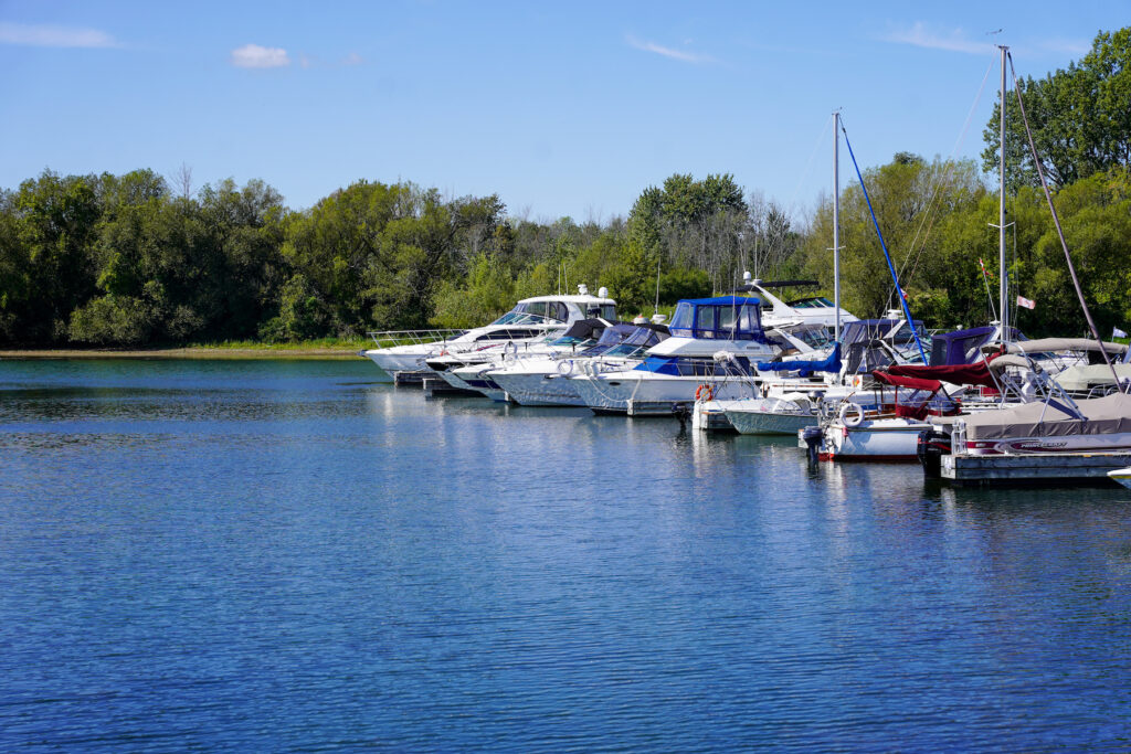 Several boats docked at Crysler Park Marina on a sunny day with clear blue skies and lush green trees in the background.